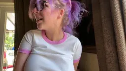 Lachendes zahnspangiges Girl mit pinker Brille und lila Haaren im engen weißen Shirt